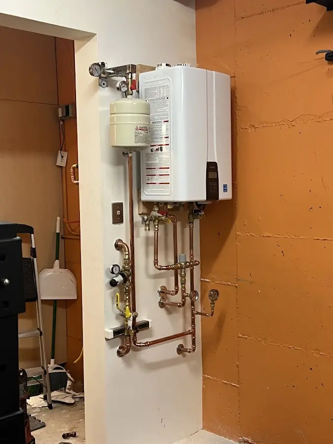 Plumbing technician inspecting water heater connections in Pingree Grove